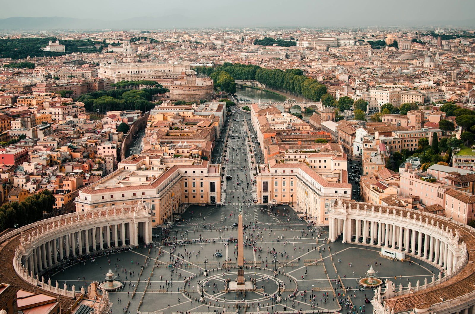 Aerial view of Saint Peter's Square in Vatican City with surrounding Roman cityscape.