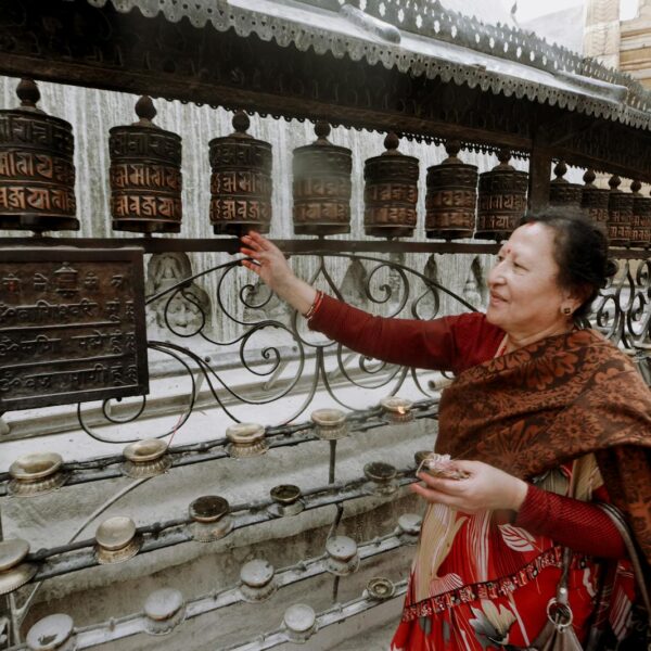 A woman in traditional attire is spinning prayer wheels at a Buddhist temple.