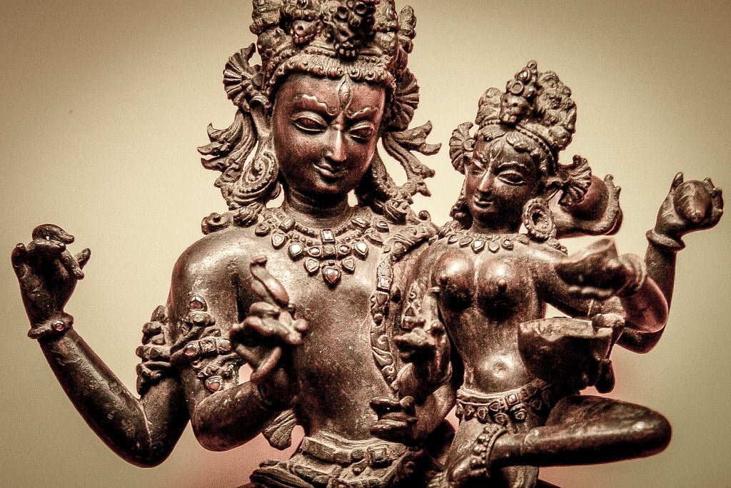 An antique bronze statue of Hindu deities with multiple arms in intricate poses and detailed adornments.