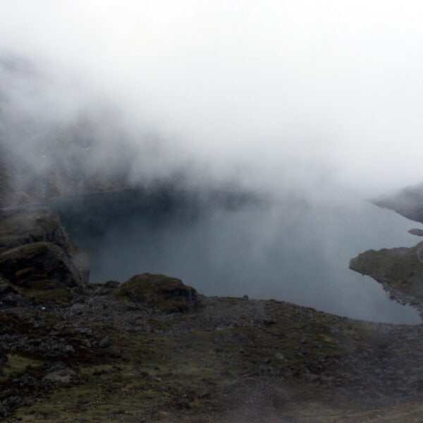 A misty mountain landscape with a serene lake partially obscured by low-hanging clouds.