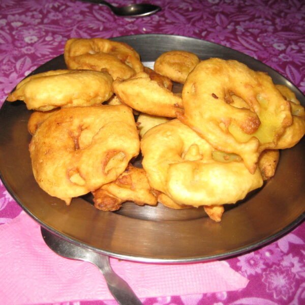 A plate of fried golden-brown fritters on a pink patterned tablecloth.