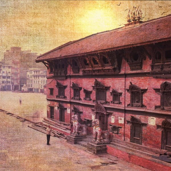 Alt text: An aged textured photograph of a traditional red brick building with detailed wood carvings and figures, possibly a temple, in an open square, with sunlight casting a warm glow on the scene.