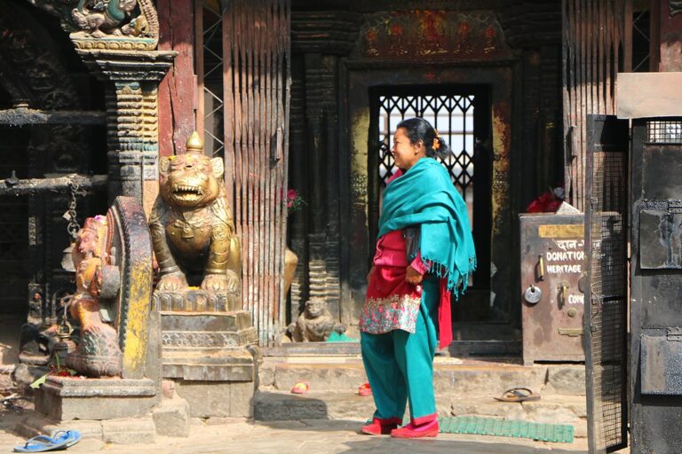 A woman in traditional attire stands in front of an ornate temple entrance, guarded by a gilded lion statue.