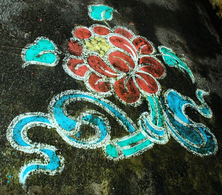 Colorful street art of a floral pattern with red, light blue, and white on a weathered concrete surface.
