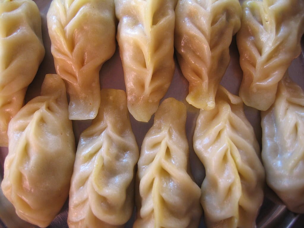 A close-up of steamed dumplings with pleated edges arranged tightly next to each other.