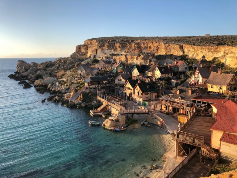 A picturesque cliffside village with rustic houses overlooking a calm sea at sunset.