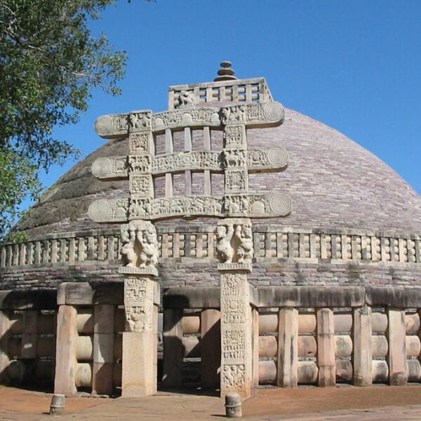 The Great Stupa at Sanchi, with its dome-shaped structure, ornate gateways, and intricate carvings against a clear blue sky.