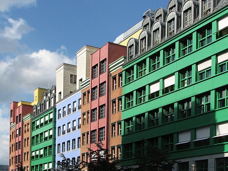 A colorful modern building with a facade painted in rainbow colors against a blue sky with clouds.