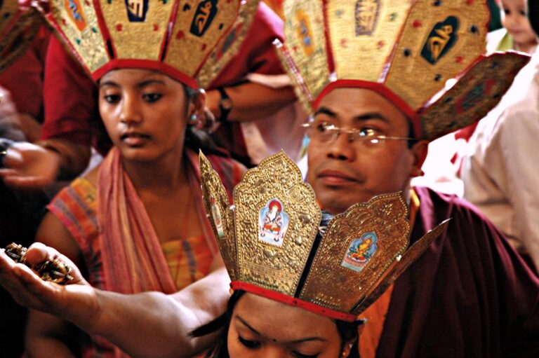 People wearing traditional Nepalese ceremonial hats with intricate designs participating in a cultural event.