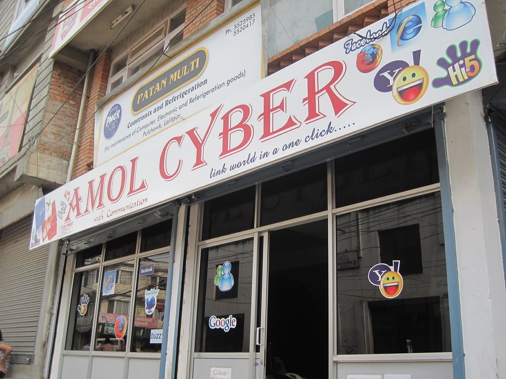 A storefront with several social media and internet browser logos, including Facebook, Twitter, Yahoo, and Google, on the sign and windows with the name "MOL CYBER" prominently displayed.