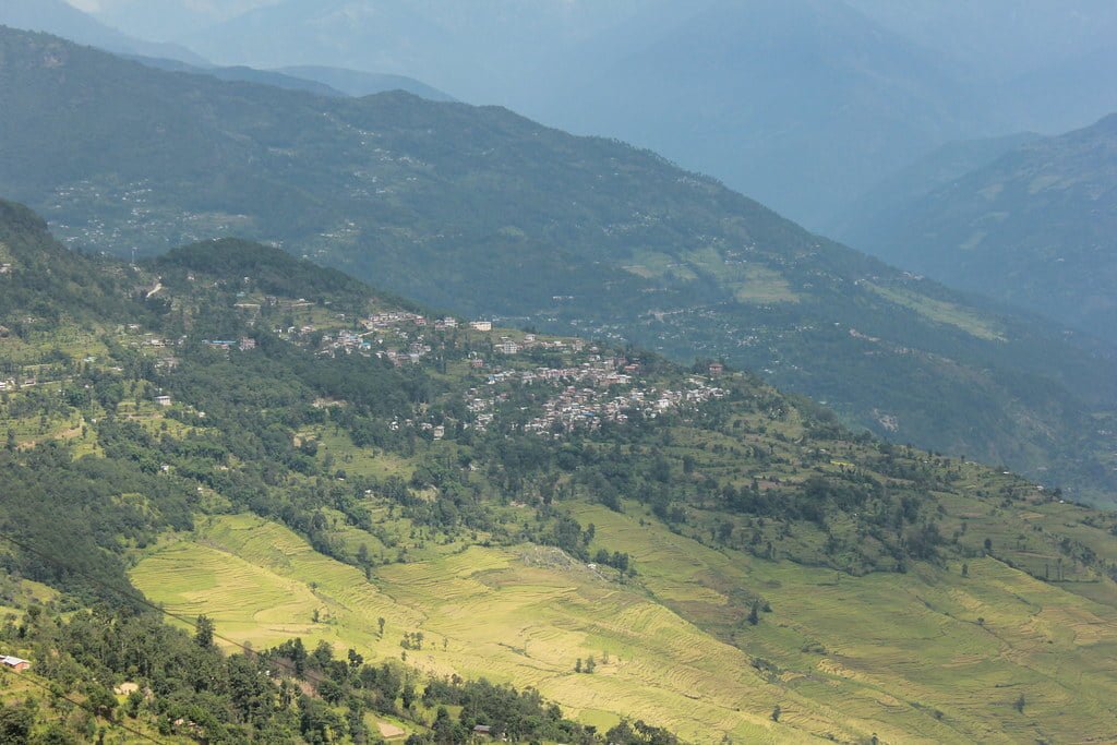 Aerial view of a terraced landscape with a small town nestled among green, rolling hills.
