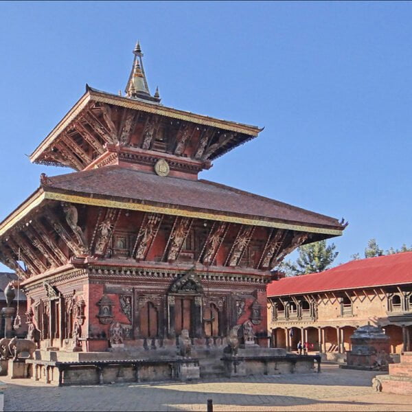 Alt text: An intricate traditional Nepalese pagoda-style temple with detailed wood carvings and tiered roofs against a clear blue sky.
