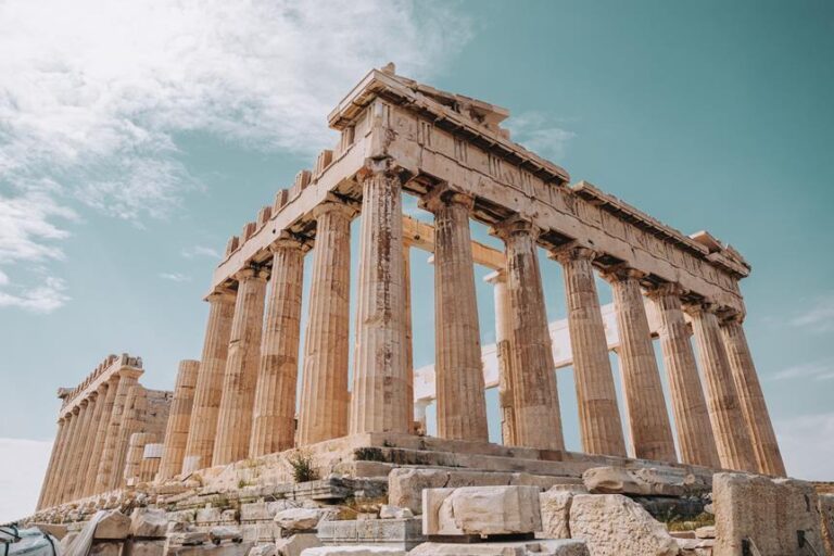 The Parthenon temple on the Acropolis of Athens, Greece, with Doric columns under a blue sky with scattered clouds.