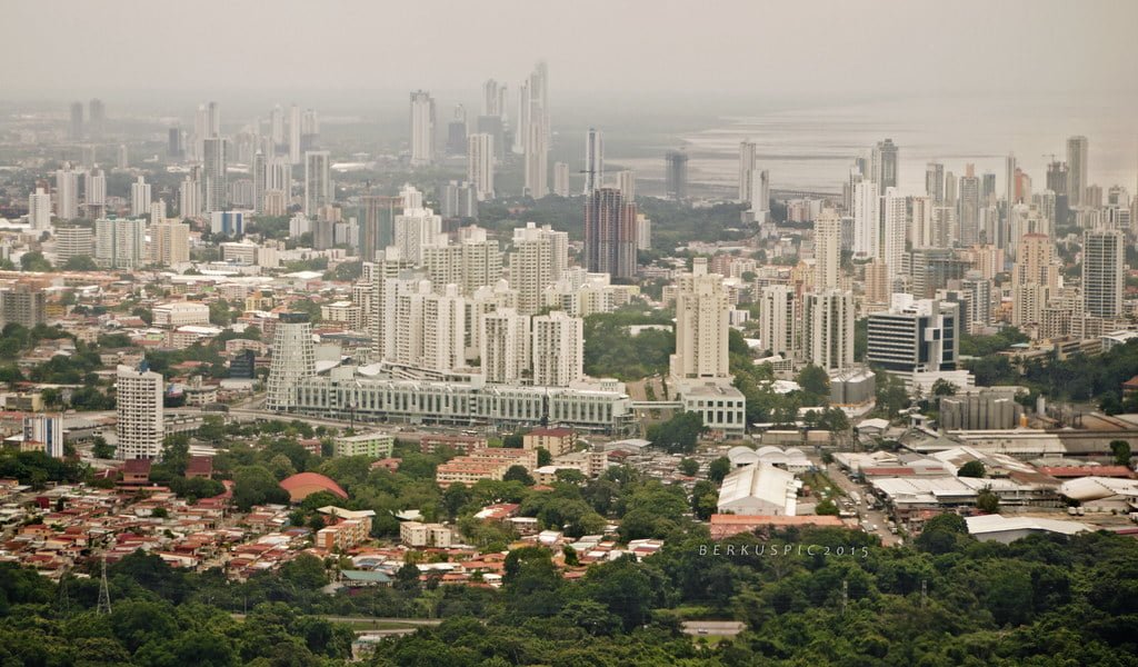 Alt text: An aerial view of a sprawling cityscape with dense clusters of high-rise buildings fading into the misty horizon.