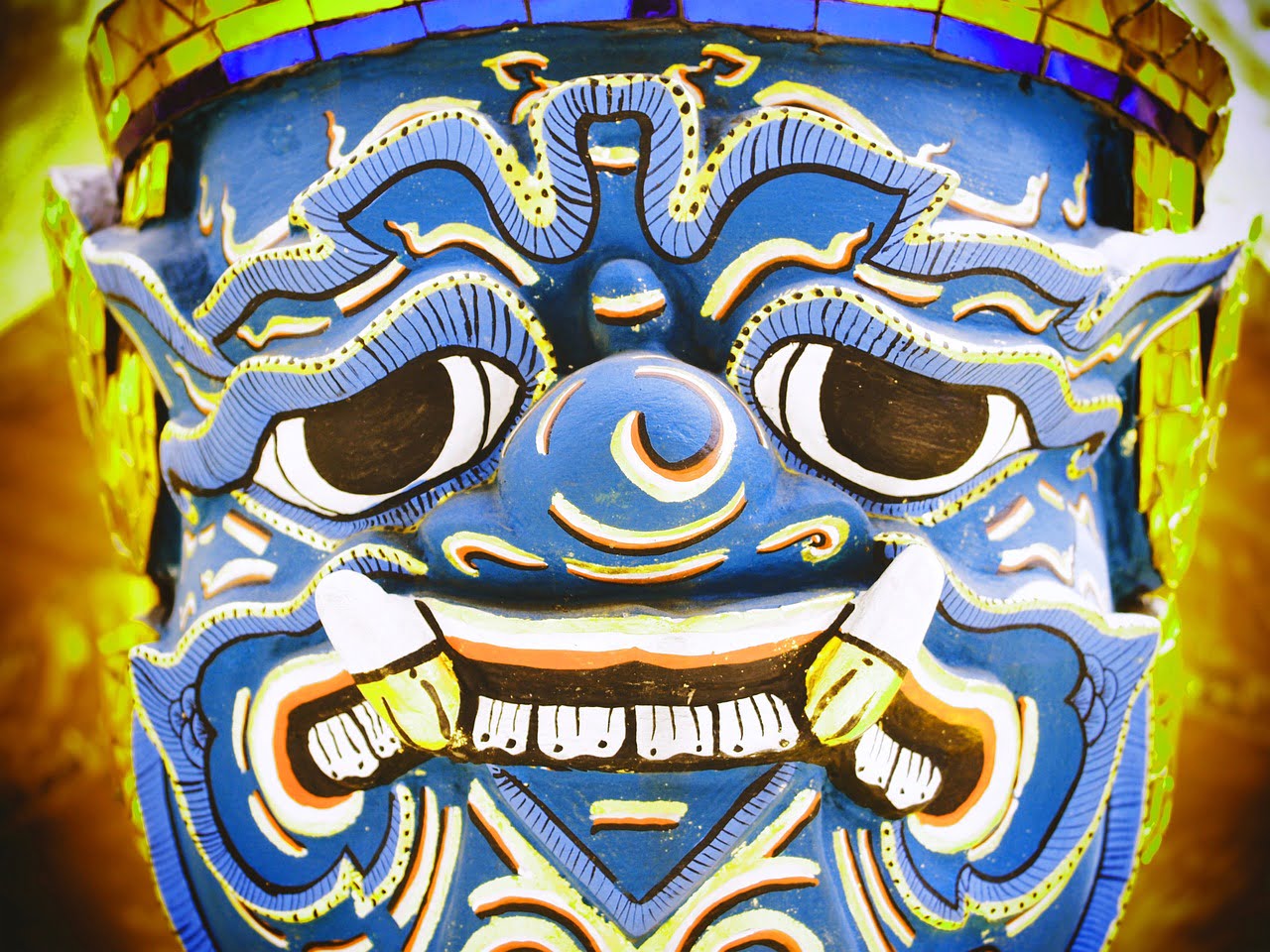 Close-up of a vibrant blue traditional demon mask with intricate patterns and fierce expression.