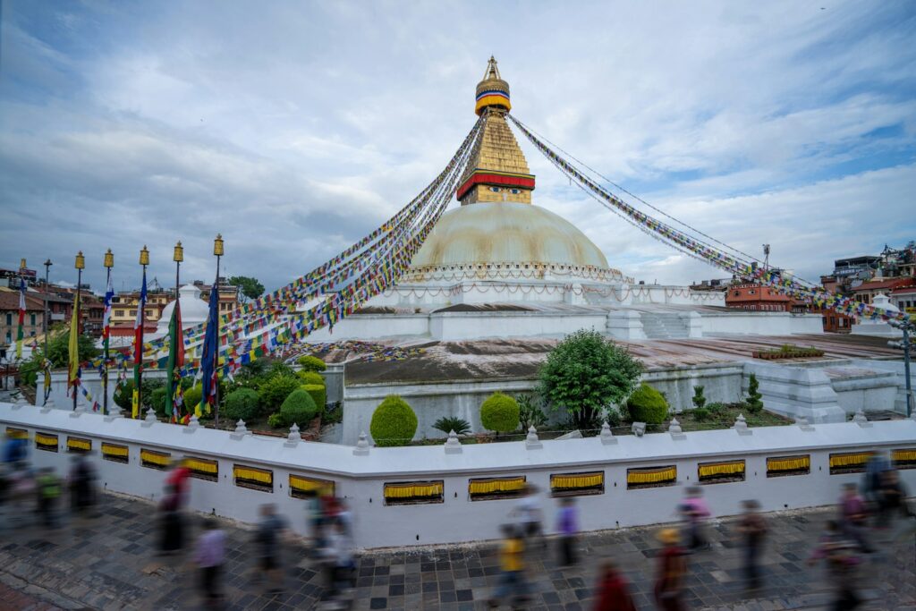 a large building with a domed roof with Boudhanath in the background