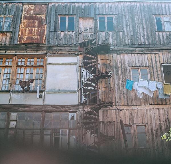 Old weathered building facade with a spiral staircase and hanging laundry.