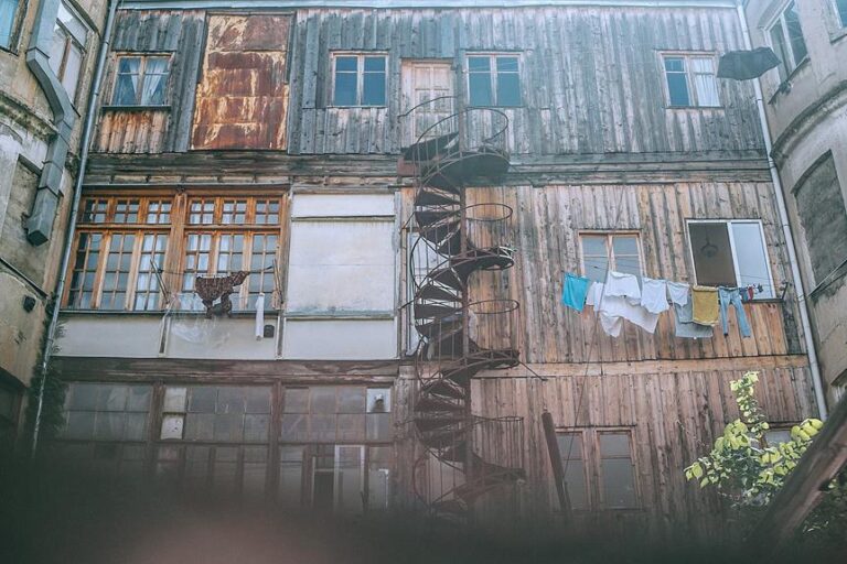 Old weathered building facade with a spiral staircase and hanging laundry.